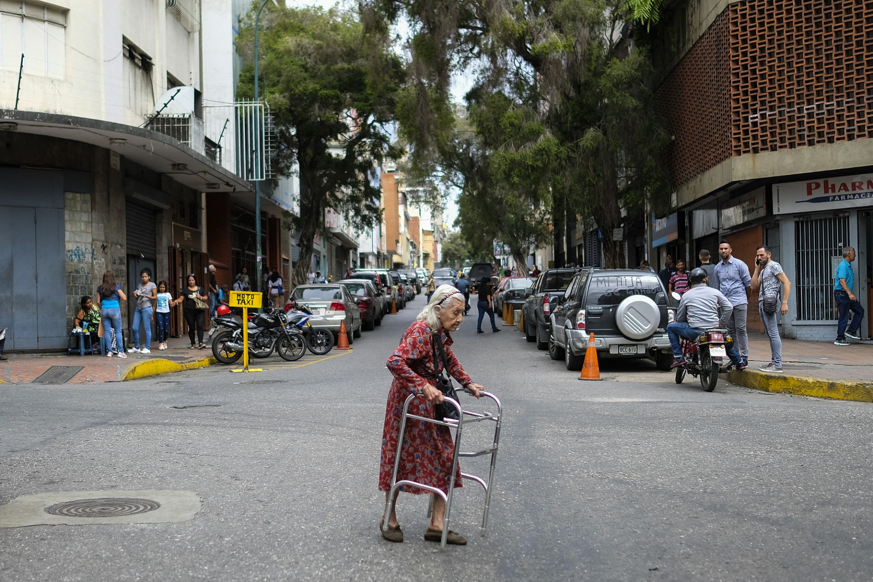 Grupo de adultos mayores venezolanos en una calle de la ciudad, algunos con aspecto de necesidad.