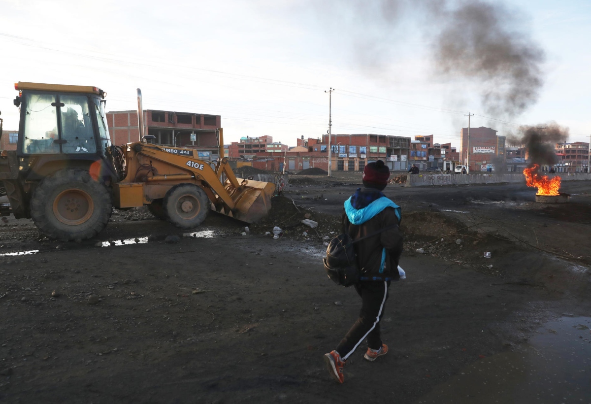 Migrantes venezolanos y colombianos esperando en una terminal de transporte en Oruro, Bolivia, con sus pertenencias.