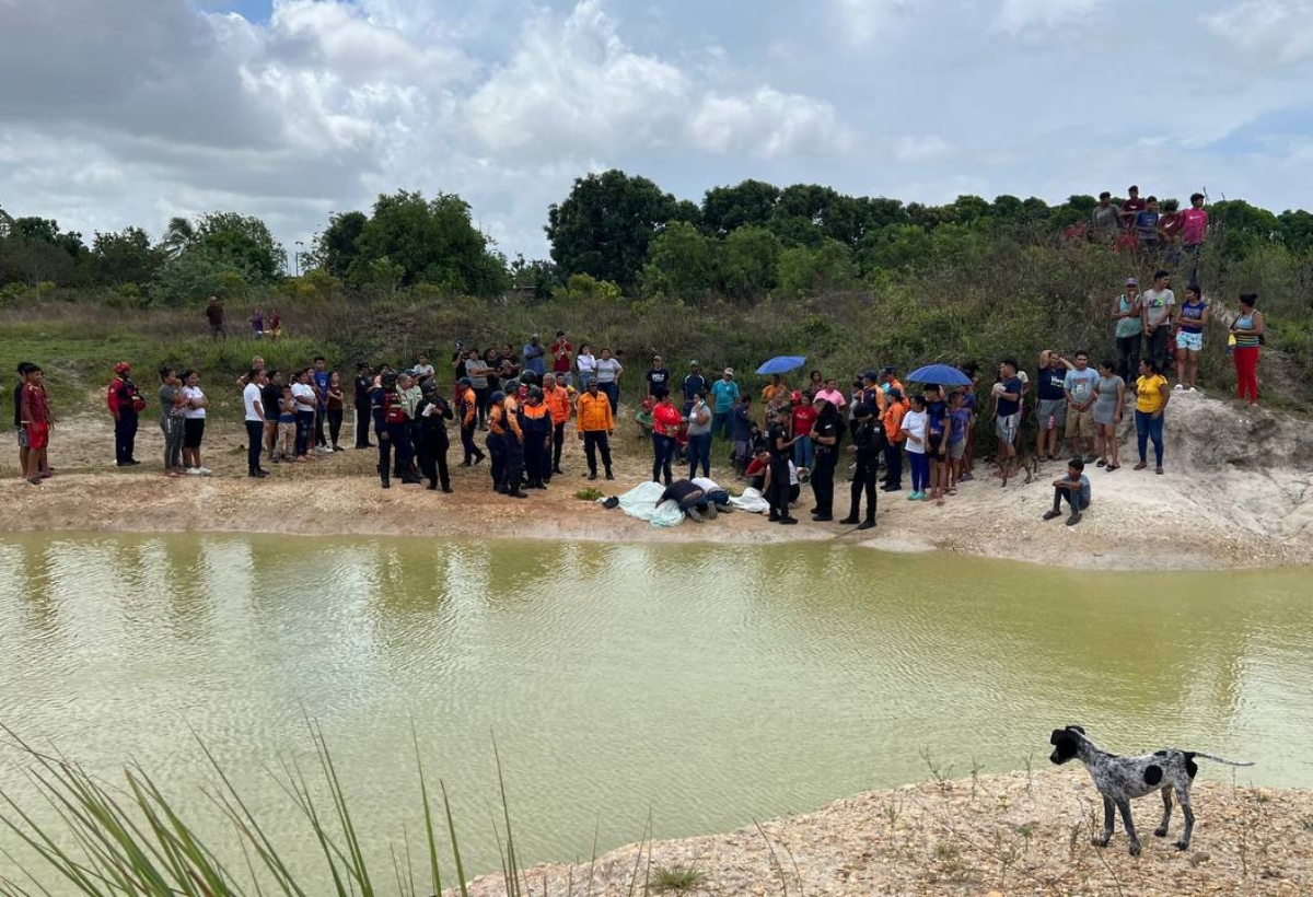 Funcionarios de rescate y seguridad en el borde de una laguna en una zona rural.