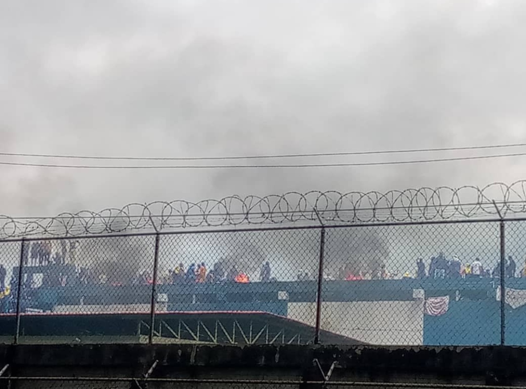 Reclusos encapuchados en los techos de una cárcel venezolana, algunos con heridas visibles, durante una protesta.
