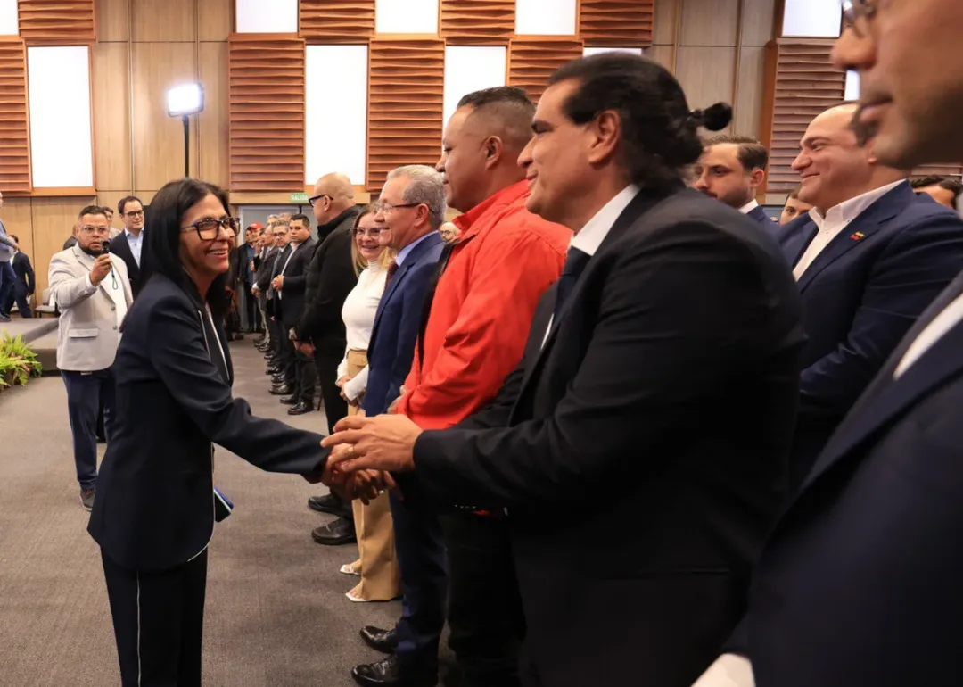 Delcy Rodríguez en un evento oficial, con Álex Saab en segundo plano, en un contexto que sugiera una relación pasada o reciente.