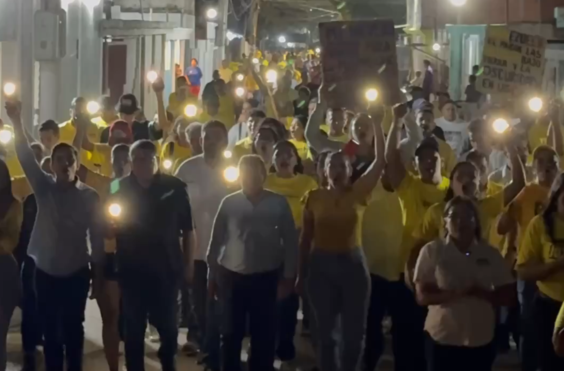 Juan Pablo Guanipa hablando en una marcha nocturna en Maracaibo, con personas a su alrededor.