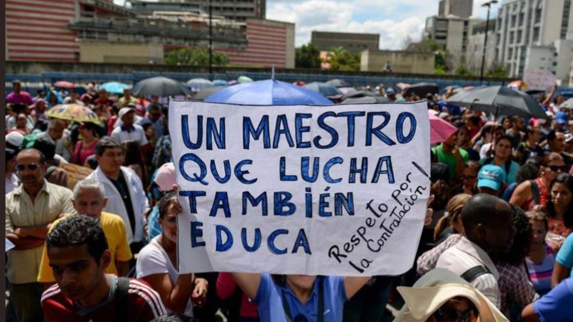 Grupo de docentes venezolanos manifestándose pacíficamente en una plaza pública, portando pancartas con sus demandas salariales.