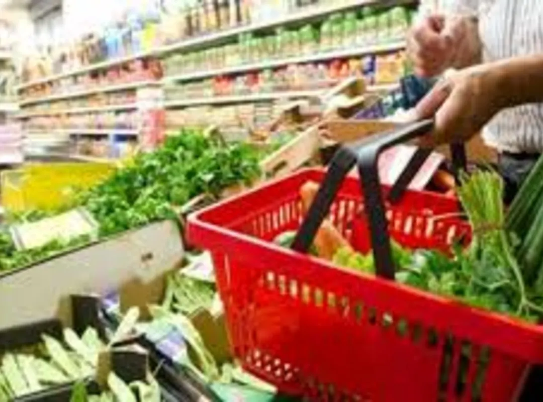 Familia venezolana observando precios de alimentos en un supermercado.