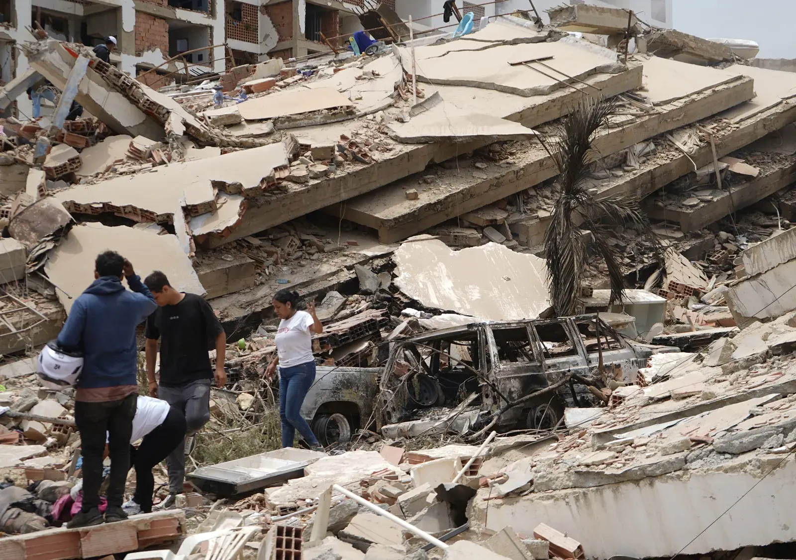 Voluntarios y residentes de La Guaira trabajan con herramientas improvisadas para remover escombros de edificios colapsados tras un fuerte terremoto.