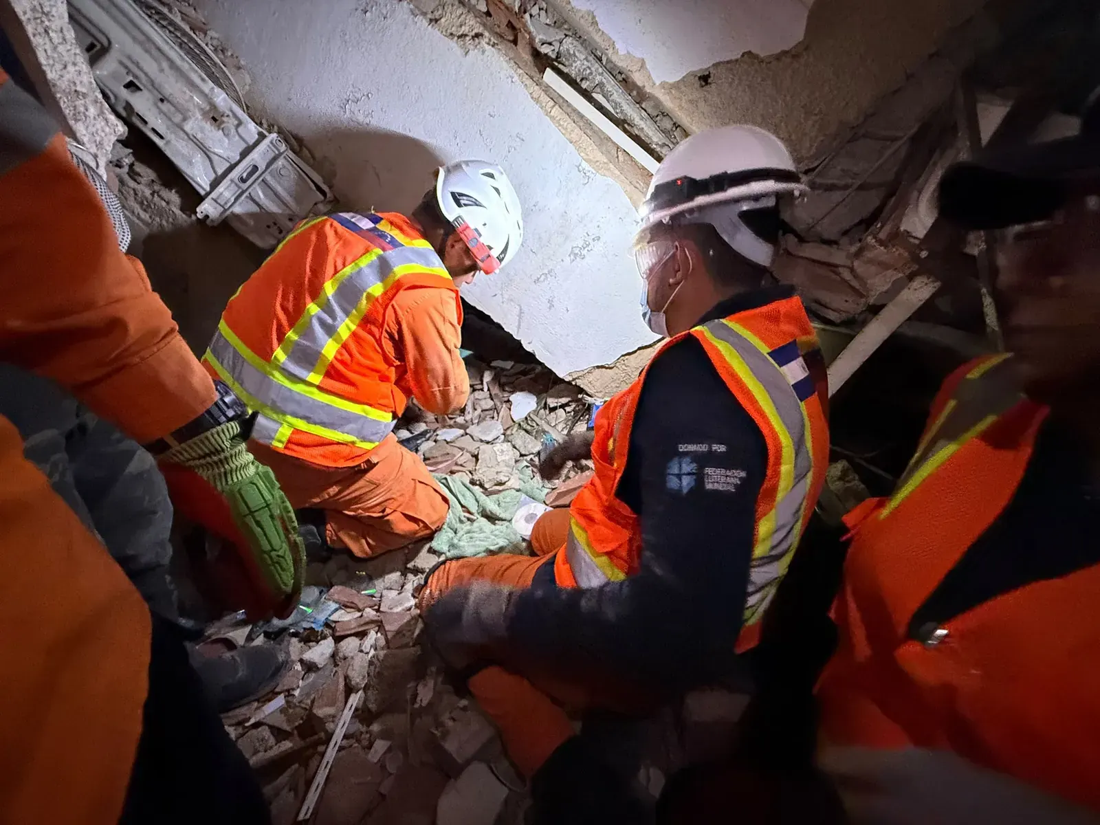 Equipo de rescatistas salvadoreños operando maquinaria pesada para remover escombros en una zona de desastre en La Guaira, Venezuela.
