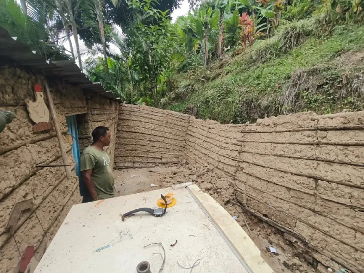 Casas rurales con daños estructurales visibles, incluyendo grietas y techos parcialmente caídos, en un paisaje montañoso.