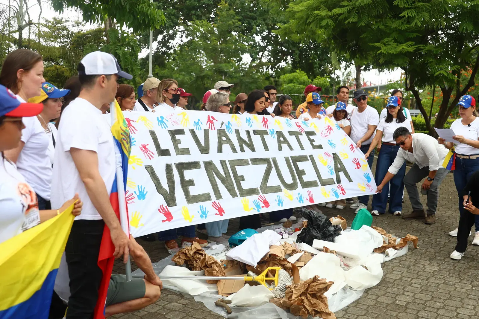 Grupo de venezolanos vestidos de blanco sosteniendo una pancarta con el mensaje "Levántate, Venezuela" durante un homenaje a las víctimas del doble terremoto en la Ciudad de