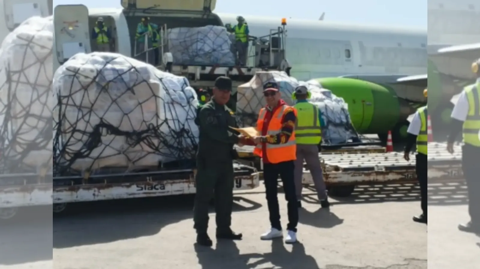 Aeronave descargando insumos humanitarios en la pista del Aeropuerto Internacional Simón Bolívar de La Guaira, con personal de seguridad y representantes consulares.