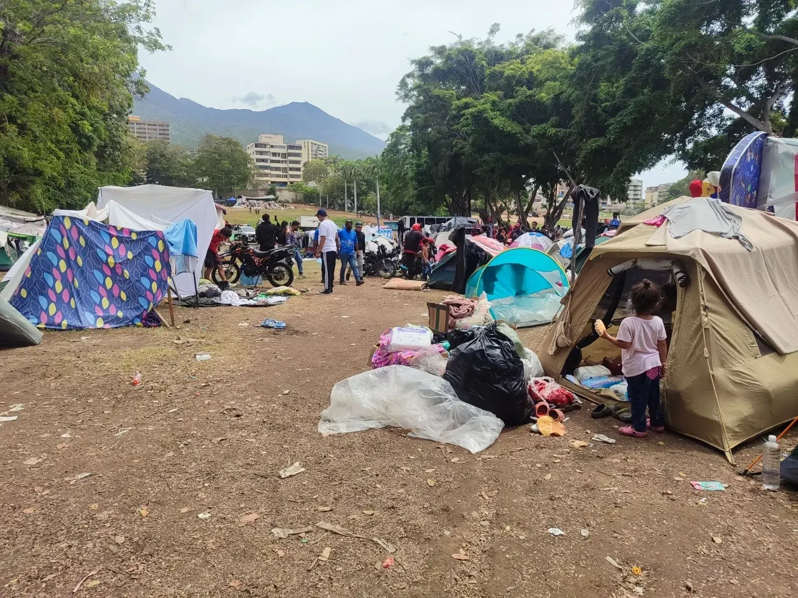 Personas acampadas en la calle frente a edificios dañados tras los terremotos de junio en Venezuela