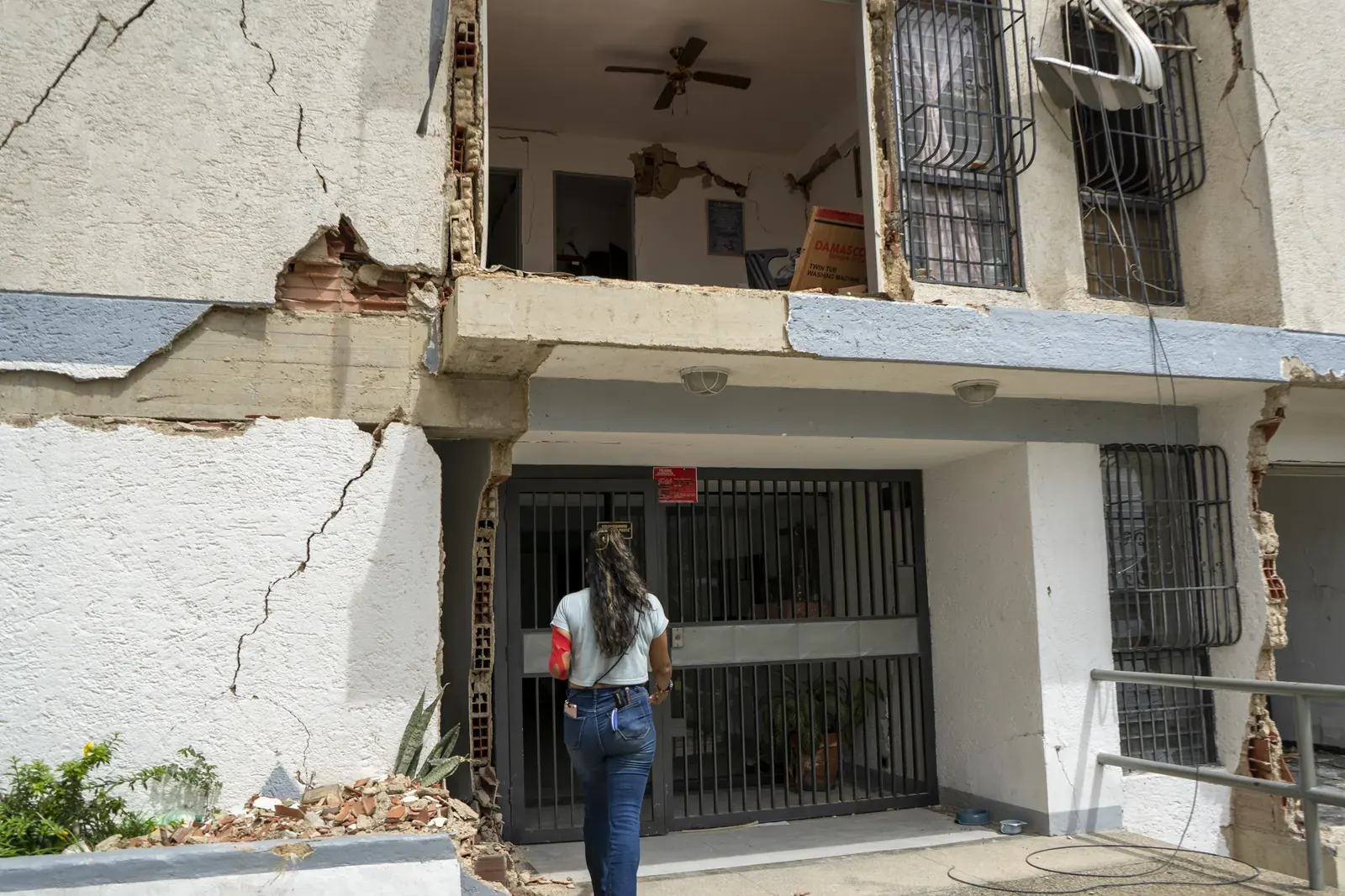 Personas observando los escombros de un edificio colapsado por un terremoto en Guarenas, Venezuela, mientras esperan poder recuperar sus pertenencias.