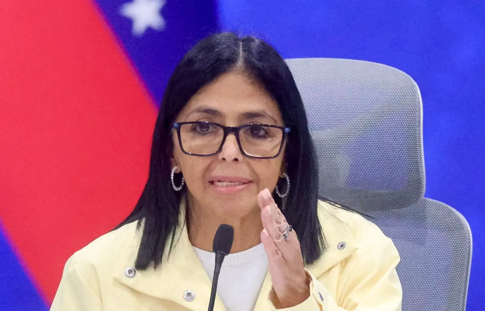 Delcy Rodríguez hablando en una conferencia de prensa, con un fondo que sugiere la respuesta a una emergencia.