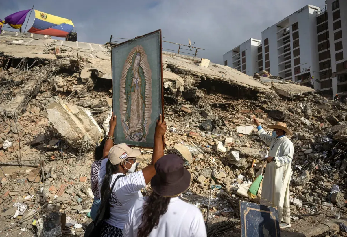 Sacerdote mexicano rezando frente a edificios dañados en La Guaira, Venezuela.