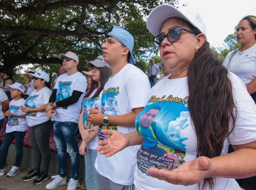 Familiares vestidos de blanco con fotografías de sus seres queridos desaparecidos en el malecón de Cúcuta, durante la conmemoración del Día Internacional de las Víctimas de